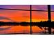 Picture window view showcasing a stunning, bright orange sunset over the tranquil lake at 318 Osprey Lakes Cir, Chuluota, FL 32766