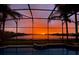 Screened-in pool area featuring a captivating orange sunset over the tranquil lake at 318 Osprey Lakes Cir, Chuluota, FL 32766