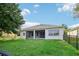 View of the back exterior with a screened patio and lush green lawn at 3514 Forest Ridge Ln, Kissimmee, FL 34741