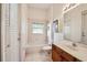 Well-lit bathroom with tub, tiled walls, and wooden vanity with sink and framed artwork at 3514 Forest Ridge Ln, Kissimmee, FL 34741