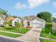 Charming home featuring a well-manicured lawn, beautiful palm trees, and a two-car garage at 3514 Forest Ridge Ln, Kissimmee, FL 34741