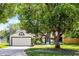 Charming single-story home with an attached two-car garage, framed by a mature tree in a grassy yard at 485 Sandpiper Ridge Dr, Orlando, FL 32835