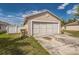 Shot of the house's two car garage with a large driveway and green grass in the front and backyard at 62 York Ct, Kissimmee, FL 34758