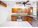 A view of the kitchen with stainless steel refrigerator and oven, wood cabinets, tile floors and granite countertops at 633 Hermits Trail, Altamonte Springs, FL 32701