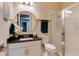 Charming bathroom with stylish wallpaper, gold fixtures, a vanity with a round mirror, and a glass-enclosed shower at 8109 Ludington Cir, Orlando, FL 32836