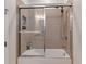 Bathroom featuring a glass-enclosed bathtub with a shower, neutral-toned tiles, and modern fixtures at 8109 Ludington Cir, Orlando, FL 32836