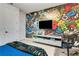 Modern bedroom with a vibrant gaming-themed wall, flat screen TV, and gaming console setup at 8109 Ludington Cir, Orlando, FL 32836