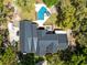 Aerial view showcasing home with dark roof, sparkling pool, and outdoor seating area amidst verdant landscape at 840 Dyson Dr, Winter Springs, FL 32708