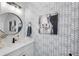 Stylish powder room features a patterned accent wall, round mirror, and elegant cow artwork at 1000 Farmstead St, Eustis, FL 32736