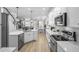 Open concept kitchen with stainless steel appliances, quartz countertops, white cabinets, and hardwood floors at 1000 Farmstead St, Eustis, FL 32736