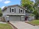 Two-story house boasting a well-manicured lawn, gray siding, attached garage and colorful pink door at 1010 Chokecherry Dr, Winter Springs, FL 32708