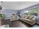 Cozy living room showcasing plush sofas, dark wood floors, and a sunlit window with neighborhood scenery at 1010 Chokecherry Dr, Winter Springs, FL 32708