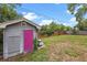 Backyard shed features a pink door and surrounding greenery in a fenced yard at 1010 Chokecherry Dr, Winter Springs, FL 32708