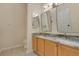 Bathroom featuring a double sink vanity with wood cabinets, granite countertop, tile floor, and dual mirrors at 10621 Golden Cypress Ct, Orlando, FL 32836