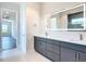 Bathroom featuring an illuminated mirror, dual sinks, and an open door leading to the bedroom at 1080 E Jack Nicklaus Ct, Kissimmee, FL 34747