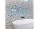 Close up on a soaking tub with patterned accent wall in modern bathroom at 1080 E Jack Nicklaus Ct, Kissimmee, FL 34747