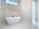 Modern bathroom with standalone tub and geometric tile accent wall with clerestory window at 1080 E Jack Nicklaus Ct, Kissimmee, FL 34747