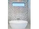 Modern bathroom with standalone tub and geometric tile accent wall with clerestory window at 1080 E Jack Nicklaus Ct, Kissimmee, FL 34747