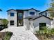 Modern two-story home with a brick driveway, three car garage, and landscaped yard at 1080 E Jack Nicklaus Ct, Kissimmee, FL 34747