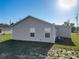 The backyard shows the gray exterior, lawn, and utility connections of this cozy home under a sunny sky at 12388 Se 106Th Ave, Belleview, FL 34420