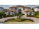Elegant two-story home with a tile roof, manicured landscaping, and a circular driveway at 13125 Casabella Dr, Windermere, FL 34786