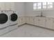 Bright laundry room with modern washer, dryer, and sink, plus white cabinetry and marble tile flooring at 13125 Casabella Dr, Windermere, FL 34786