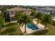 An aerial view of a blue pool, spa, light beige patio, and palm trees in the backyard of a luxury home at 13125 Casabella Dr, Windermere, FL 34786
