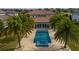 An aerial view of a blue pool, spa, light beige patio, and palm trees in the backyard of a luxury home at 13125 Casabella Dr, Windermere, FL 34786