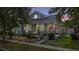 Charming gray single-Gathering home at dusk featuring a covered front porch, manicured landscaping and an American flag at 14131 Paradise Tree Dr, Orlando, FL 32828