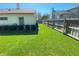 Wide angle of the side yard showcasing green grass, trimmed bushes, and a wooden fence at 1474 Thornhill Cir, Oviedo, FL 32765