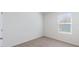 Neutral bedroom featuring beige carpet, baseboards, and a window allowing for natural light at 186 Amberwood Way, Umatilla, FL 32784