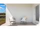 Comfortable front porch featuring two gray cushioned chairs with striped pillows and a white door at 186 Amberwood Way, Umatilla, FL 32784