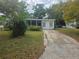 A single-story home with a screened-in porch and a concrete driveway surrounded by mature trees at 2507 Lafayette Ave, Winter Park, FL 32789