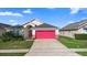 Charming single-story home featuring a vibrant pink garage door, well-manicured lawn, and inviting curb appeal at 2535 Oneida Loop, Kissimmee, FL 34747