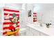 Bright bathroom with a Mickey Mouse themed shower curtain, white cabinets, and a large mirror at 2618 Calistoga Ave, Kissimmee, FL 34741