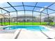 A sparkling swimming pool surrounded by a screen enclosure and lush green grass and lounge chairs at 2618 Calistoga Ave, Kissimmee, FL 34741