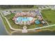 Aerial view of a community pool with a splashpad, sun loungers, and lush landscaping by a tranquil lake at 3041 Cardillino Way, Kissimmee, FL 34741