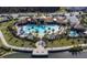 Aerial view of a community pool with a slide, lounge areas, and a clubhouse nestled alongside a serene lake at 3041 Cardillino Way, Kissimmee, FL 34741