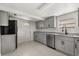 Well-lit kitchen with gray cabinets, granite counters, stainless appliances, tile floors, and a back door at 3137 East St, Oviedo, FL 32765