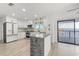 Modern kitchen boasts an island, white cabinets, stainless appliances, and a sliding glass door to the outdoor area at 3216 John Anderson Dr, Ormond Beach, FL 32176
