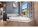 Bathroom with a garden tub, tile surround, large window, and patterned curtains at 4932 Eastlake Vista Dr, St Cloud, FL 34771
