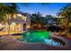 Backyard pool and patio area with lush greenery, sun umbrella, and an elegant two-story home in background at 511 Woodlawn Blvd, Orlando, FL 32801