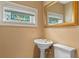 Powder room showcasing a pedestal sink, a decorative window, and a gold-framed mirror at 511 Woodlawn Blvd, Orlando, FL 32801