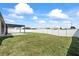Spacious backyard with a well-maintained lawn, privacy fence, and a covered patio area at 5707 Fischer Dr, Lakeland, FL 33812