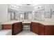 Bright bathroom featuring dual sinks, wood cabinets, vanity area, and large mirrors with overhead lighting at 5707 Fischer Dr, Lakeland, FL 33812