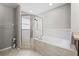 Bathroom showcasing a large soaking tub with tiled surround and a glass-enclosed shower area at 5707 Fischer Dr, Lakeland, FL 33812