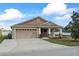 Front exterior of a home featuring a two-car garage, stone accents, and manicured landscaping at 5707 Fischer Dr, Lakeland, FL 33812