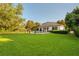 Sprawling backyard with lush green lawn, pool, water slide, and mature trees, ideal for outdoor activities at 6143 Cartmel Ln, Windermere, FL 34786
