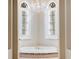 Elegant bathroom with a soaking tub, chandelier, and natural light from two arched windows with shutters at 6143 Cartmel Ln, Windermere, FL 34786