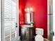 Charming powder room features a vibrant red wall, a decorative mirror, and a classic vanity at 6143 Cartmel Ln, Windermere, FL 34786